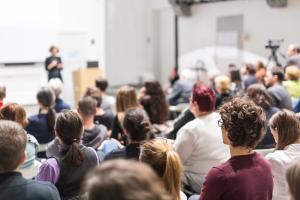 Students gathered for lecture; in background, standing lecturer